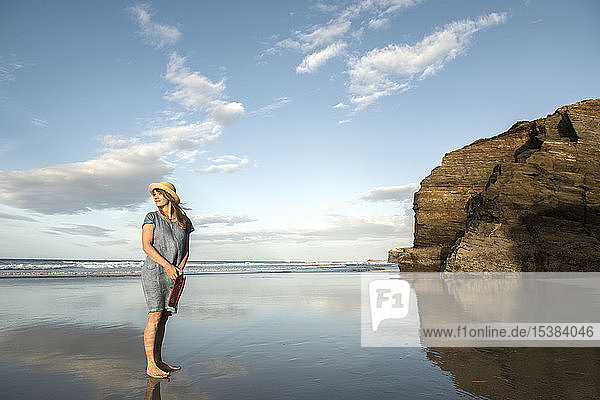 Frau steht am Strand und schaut aufs Meer