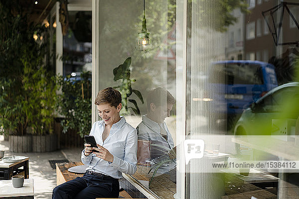 Geschäftsfrau benutzt Mobiltelefon in einem Café
