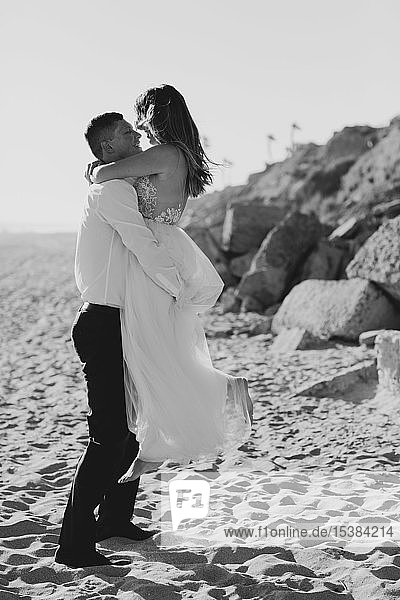 Happy bride and groom hugging on the beach