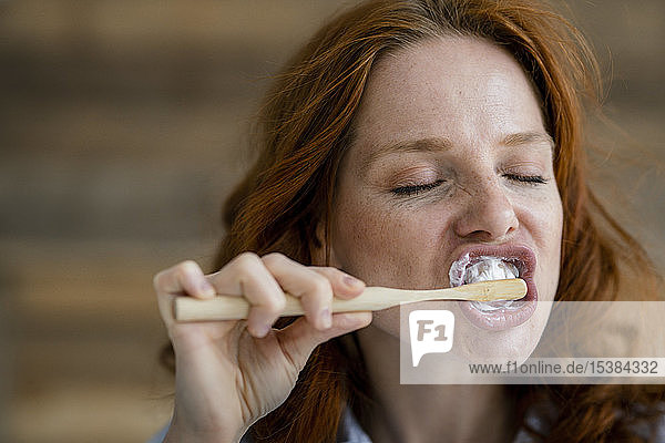 Porträt einer rothaarigen Frau beim Zähneputzen
