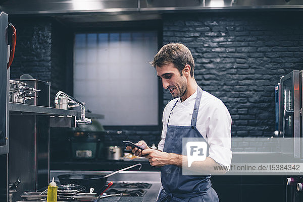 Küchenchef mit Smartphone in der Küche eines Restaurants