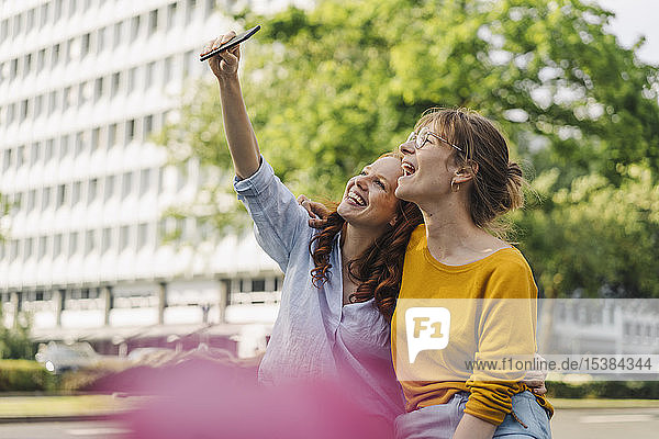 Zwei glückliche Freundinnen  die in der Stadt ein Selfie machen