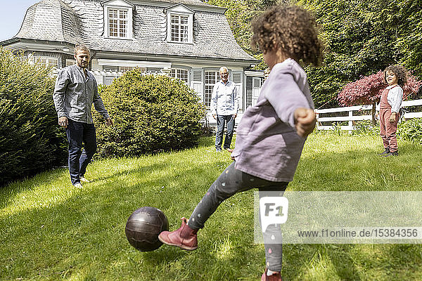 Glückliche Grossfamilie spielt Fussball im Garten