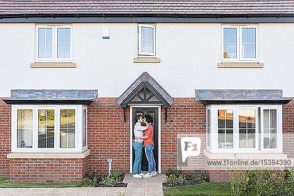 Ein Paar küsst sich vor der Haustür seines Hauses
