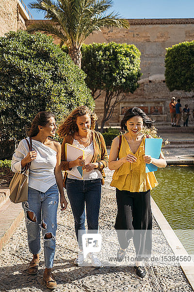 Three happy female friends walking around in a formal garden