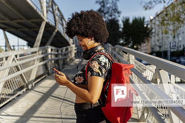 Weibliche Afroamerikanerin mit Kopfhörern und Smartphone beim Musikhören