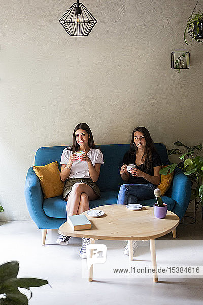 Zwei junge Freundinnen sitzen auf einer Couch in einem Cafe