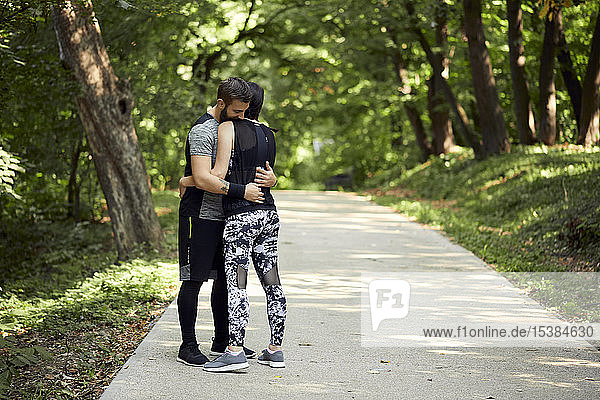 Sportliches Paar umarmt sich auf Waldweg