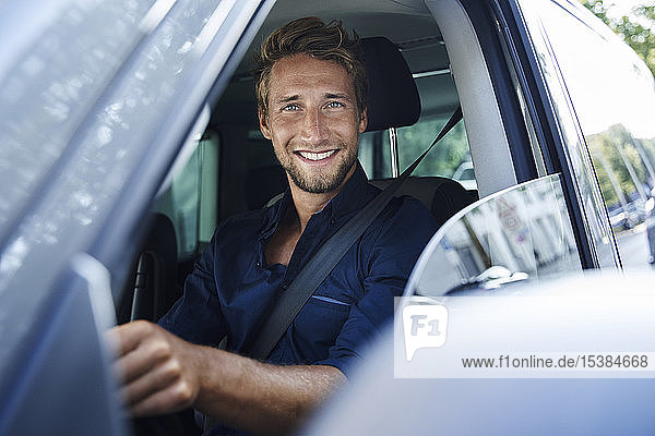 Porträt eines lächelnden jungen Mannes im Auto
