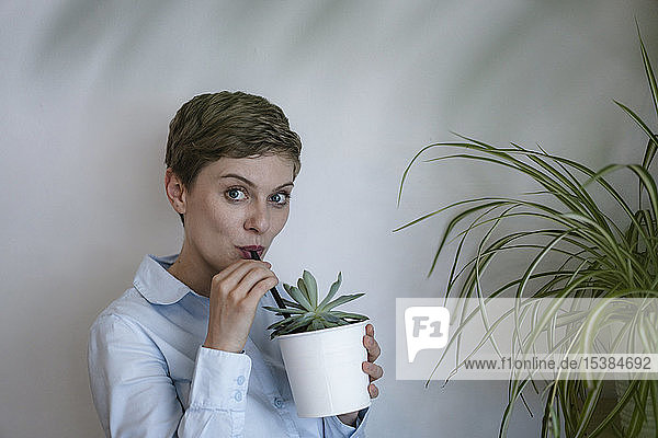 Porträt einer Geschäftsfrau  die aus Topfpflanzen trinkt