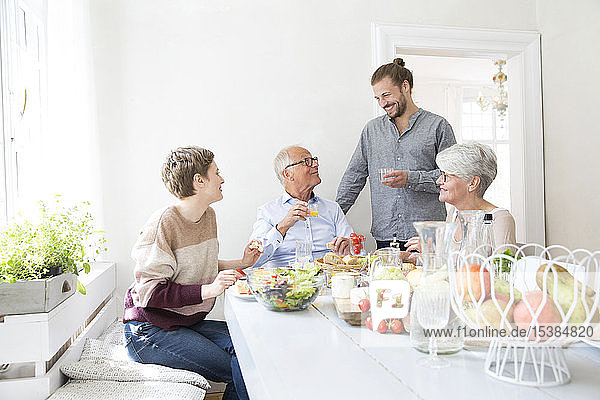 Glückliches älteres Ehepaar mit erwachsenen Kindern beim Mittagessen zu Hause