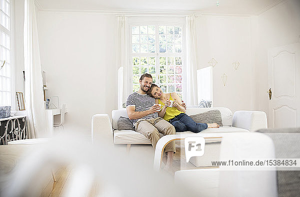 Glückliches junges Paar sitzt zu Hause auf dem Sofa