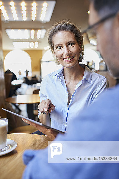 Smiling woman and man with tablet in a cafe