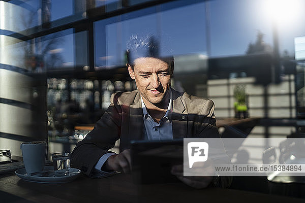 Businessman using tablet behind the window in a cafe