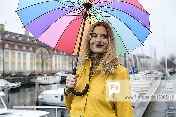 Dänemark Kopenhagen lächelnde Frau mit buntem Regenschirm im Stadthafen