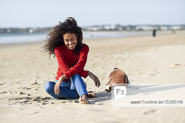 Happy young woman sitting on the beach