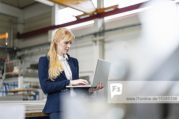 Geschäftsfrau mit Laptop in der Fabrik