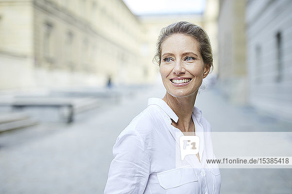 Porträt einer lächelnden Frau mit weißem Hemd in der Stadt
