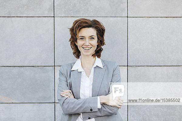 Porträt einer jungen selbstbewussten Geschäftsfrau vor grau gekachelter Wand