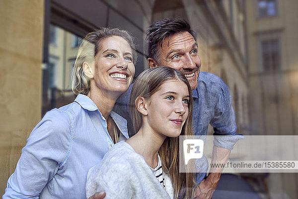 Portrait of happy family behind windowpane