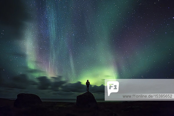 Norway  Lofoten Islands  Eggum  man standing on rock and watching northern lights