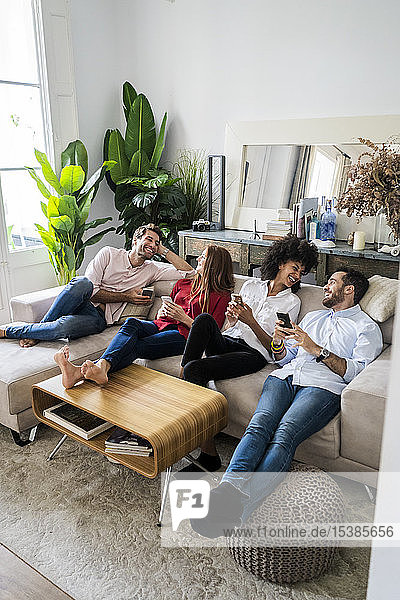 Freunde sitzen auf der Couch  arbeiten zwanglos zusammen  benutzen Smartphones
