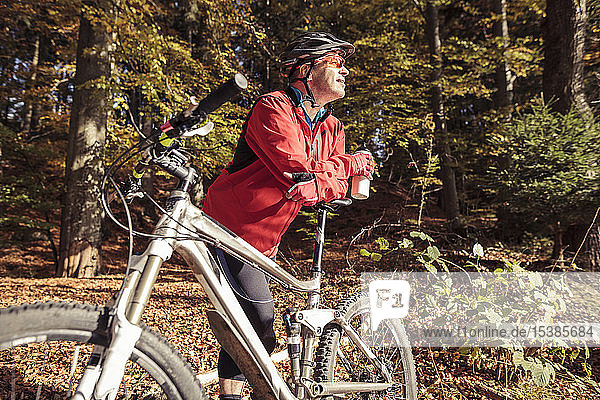 Mann mit Mountainbike bei einer Pause im Wald