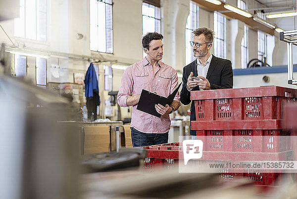 Zwei Männer in der Fabrik untersuchen Werkstück