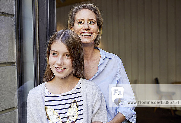 Portrait of happy mother with daughter at open door