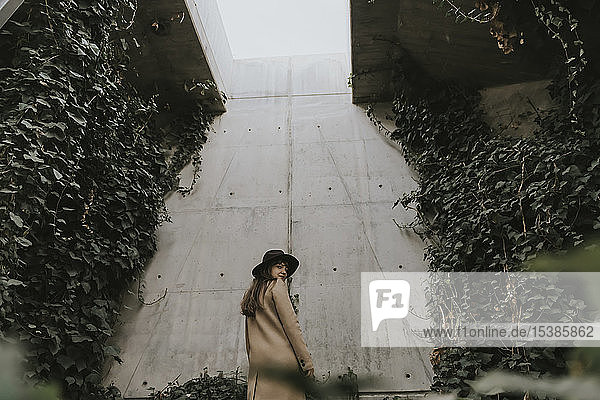 Young woman in underground tunnel  concrete wall full of plants
