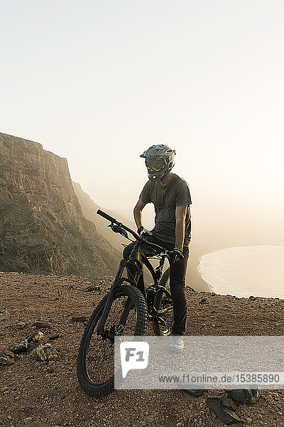Spanien  Lanzarote  Mountainbiker auf einer Fahrt an der Küste bei Sonnenuntergang
