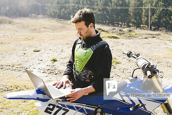Portrait of motocross driver using laptop