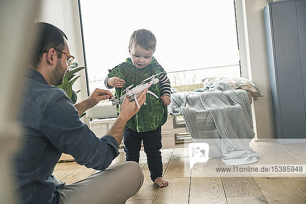 Boy in a costume and father playing with a drone at home