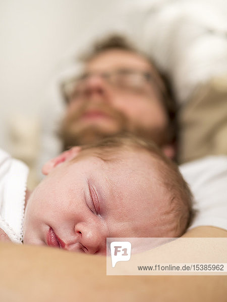 Father and newborn girl sleeping