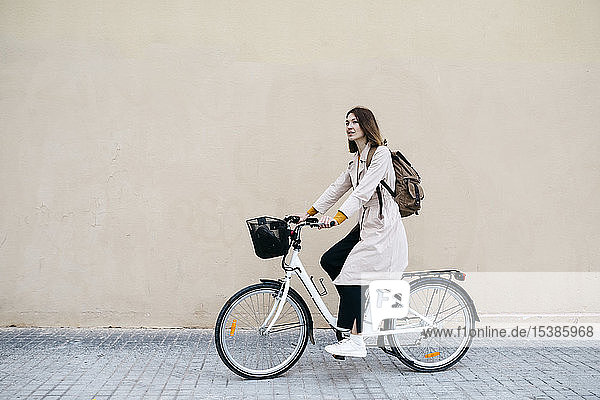 Woman riding e-bike along a wall