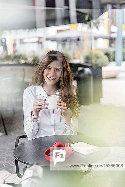 Junge Geschäftsfrau sitzt im Café  arbeitet und trinkt Kaffee