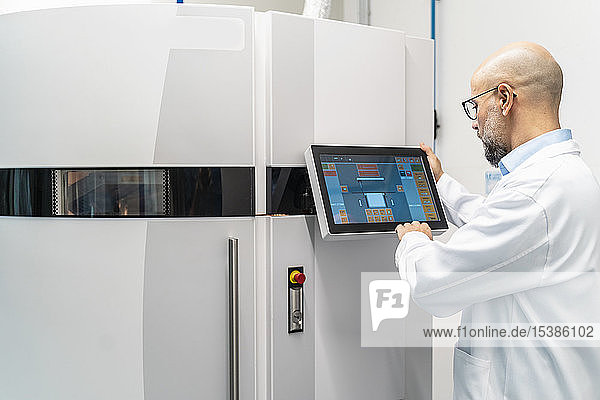 Techniker im Laborkittel bei der Bedienung eines 3D-Druckers
