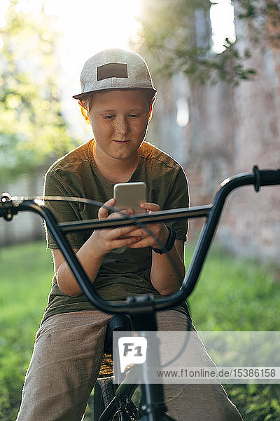 Boy with bmx bike using cell phone