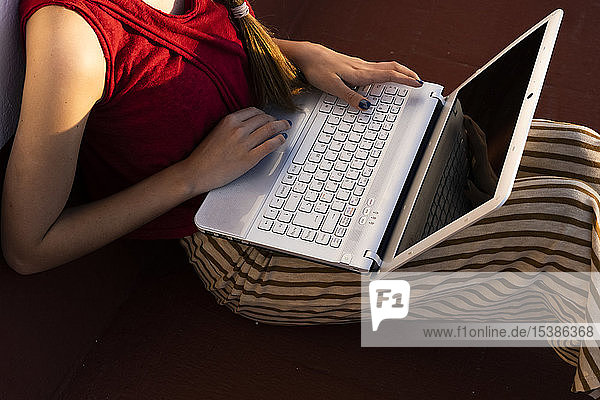 Nahaufnahme einer Teenagerin  die mit einem Laptop im Freien sitzt