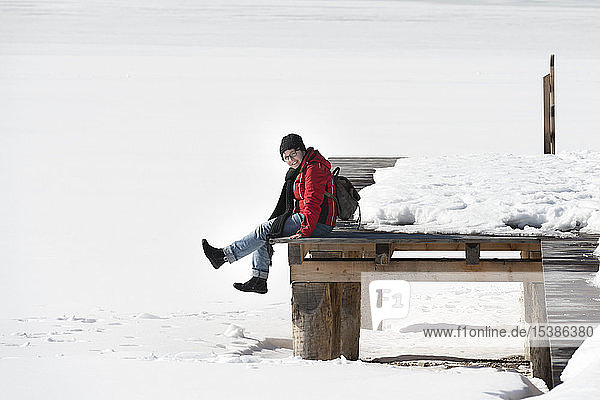 Austria  Tyrol  Achensee  woman sitting on jetty in winter