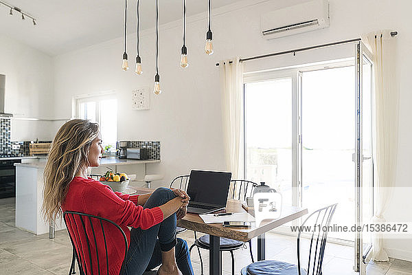 Frau benutzt Laptop auf dem Esstisch im modernen Haus