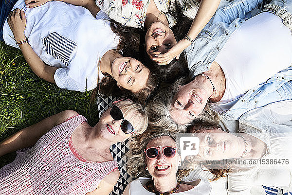 Draufsicht auf eine glückliche Gruppe von Frauen  die auf einer Wiese liegen