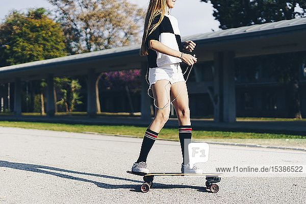 Spanien  Teenager-Mädchen fährt Skateboard auf einer Straße