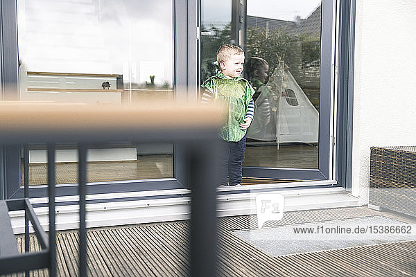 Happy boy in a costume standing at terrace door at home