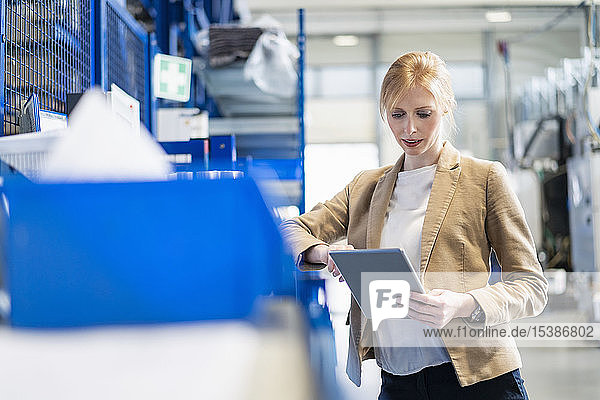Geschäftsfrau mit Tablette im Fabriklager