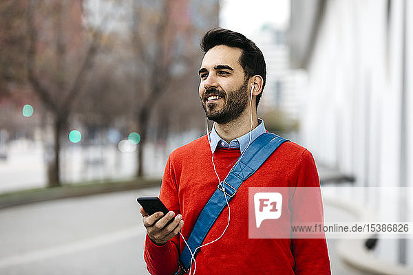 Casual businessman commuiting in the city  using earphones and smartphone