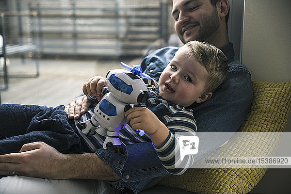 Vater und Sohn spielen zu Hause mit einem Spielzeugroboter