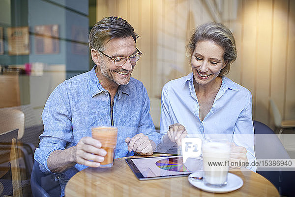 Glückliche Frau und Mann benutzen Tabletten in einem Café