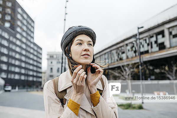 Porträt einer Frau  die in der Stadt einen Fahrradhelm aufsetzt