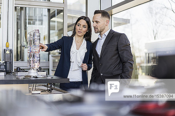 Businessman and businesswoman talking at a machine in modern factory